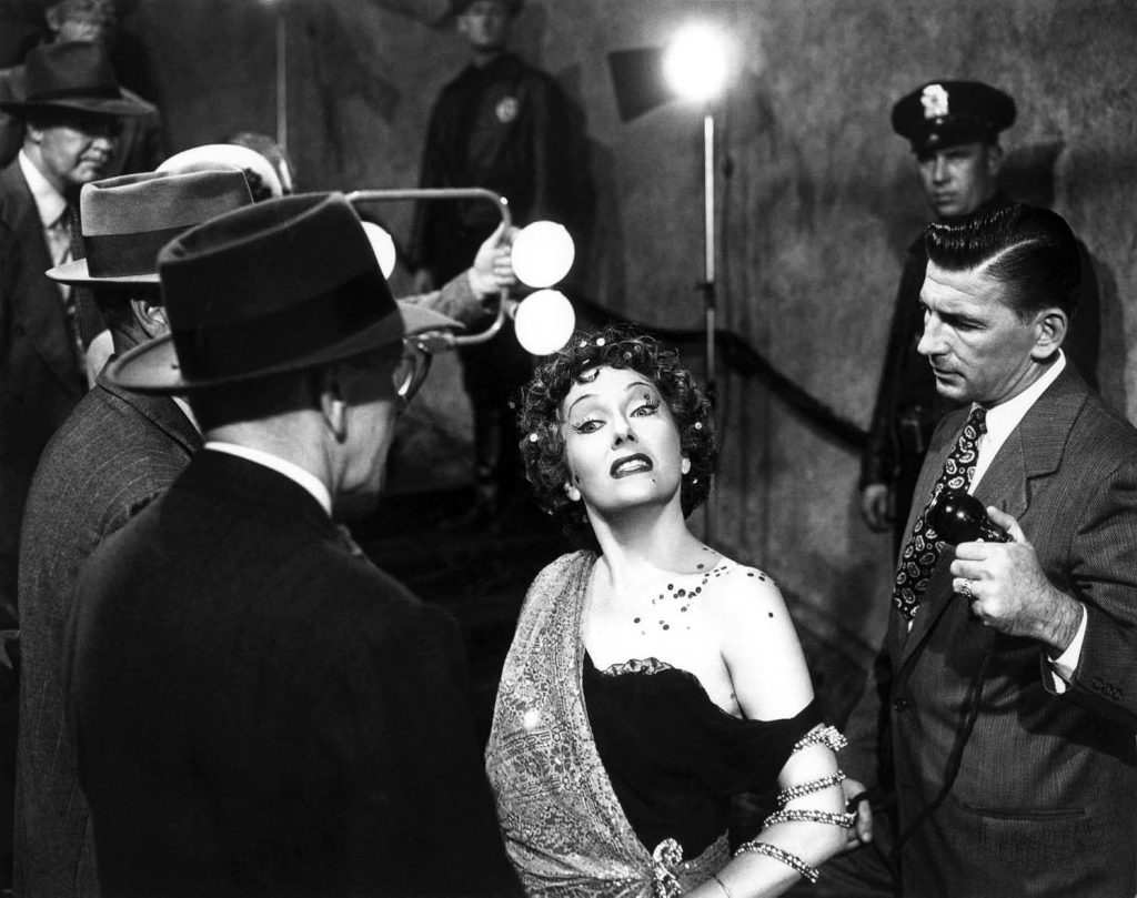 La simbólica escena en la cual la diva acude a los estudios de rodaje de DeMille y es “atacada” por un micrófono. 